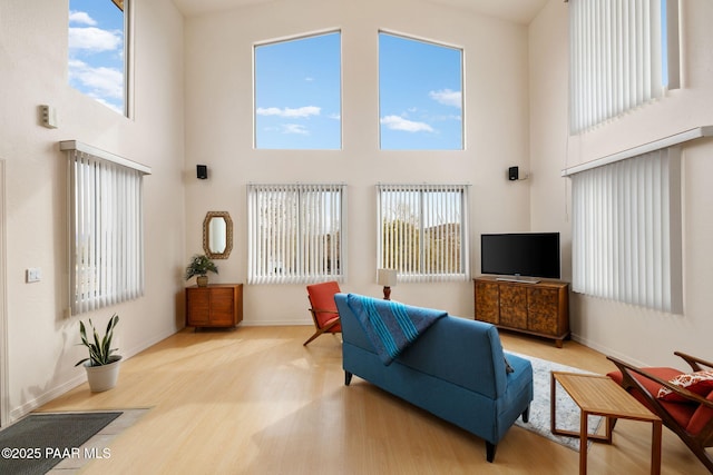 living area featuring a high ceiling, wood finished floors, and baseboards