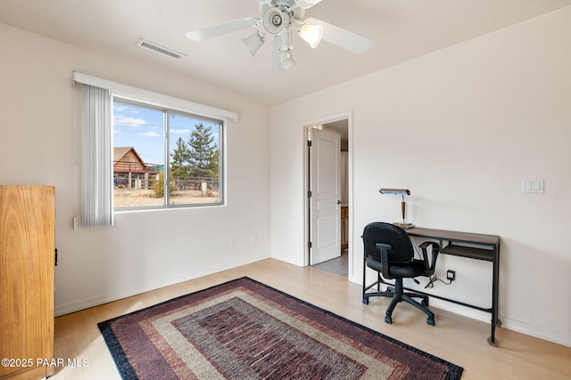 home office featuring a ceiling fan, wood finished floors, visible vents, and baseboards