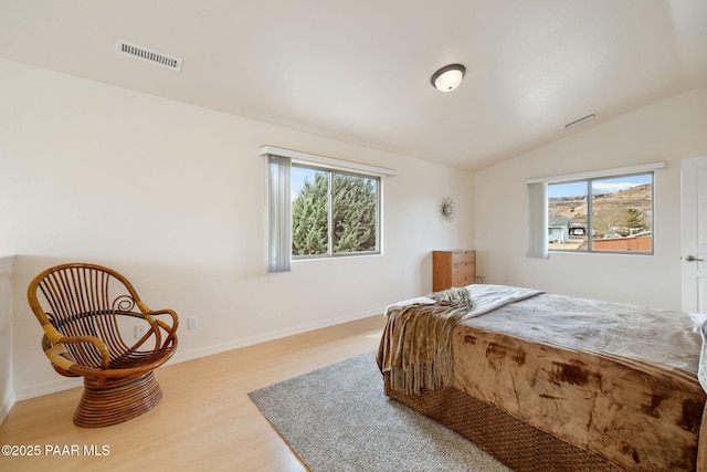 bedroom with lofted ceiling, wood finished floors, visible vents, and baseboards