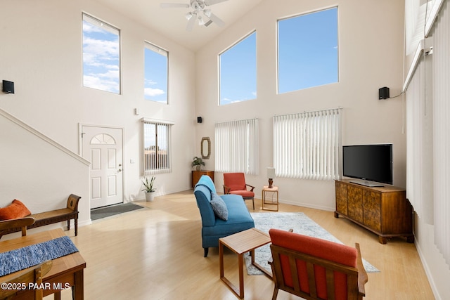 living room with light wood finished floors, baseboards, and a ceiling fan