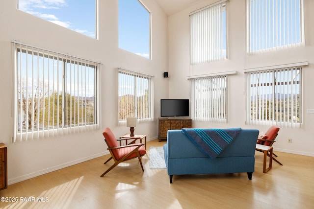 living area with a wealth of natural light, baseboards, and wood finished floors