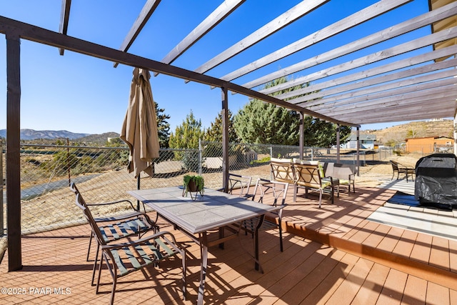 deck featuring outdoor dining area, fence, a mountain view, and a pergola