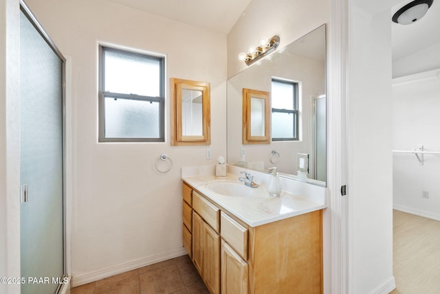 bathroom featuring tile patterned floors, an enclosed shower, baseboards, and vanity