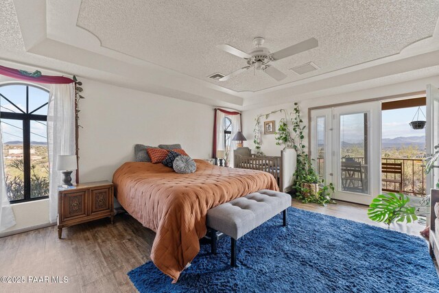 969 S Saguaro Dr, Wickenburg, AZ 85390 - bedroom featuring access to outside, a textured ceiling, wood finished floors, a tray ceiling, and a ceiling fan