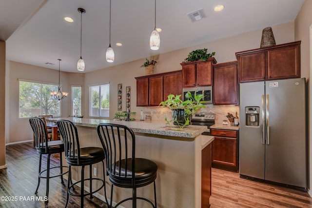 12993 E Toro St, Dewey-Humboldt, AZ 86327 - kitchen with appliances with stainless steel finishes, decorative backsplash, a kitchen breakfast bar, a center island, and light wood-style floors
