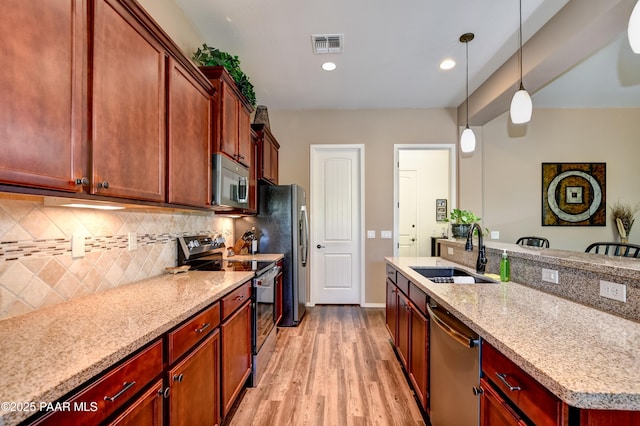 12993 E Toro St, Dewey-Humboldt, AZ 86327 - kitchen with stainless steel appliances, decorative backsplash, light wood-type flooring, hanging light fixtures, and light stone countertops
