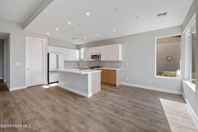 kitchen with freestanding refrigerator, backsplash, visible vents, and plenty of natural light