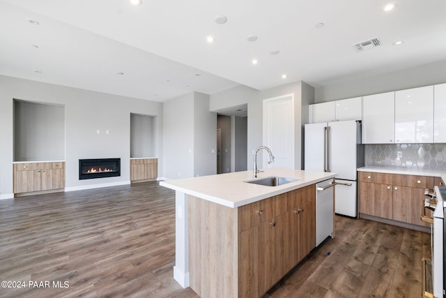 kitchen with dark wood finished floors, visible vents, a kitchen island with sink, a sink, and stainless steel appliances