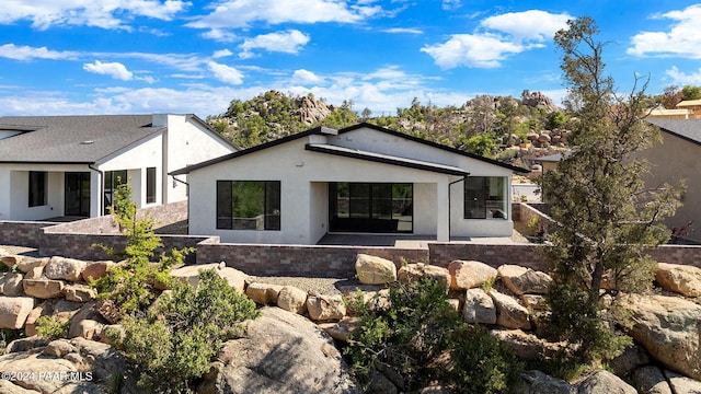 rear view of property featuring stucco siding and fence