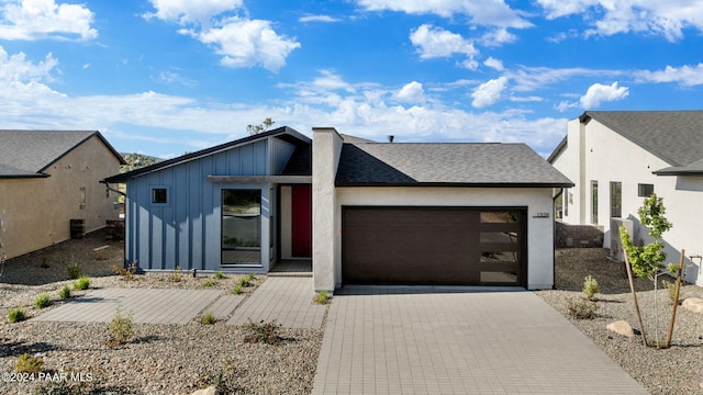 view of front of home with an attached garage, a shingled roof, board and batten siding, and driveway