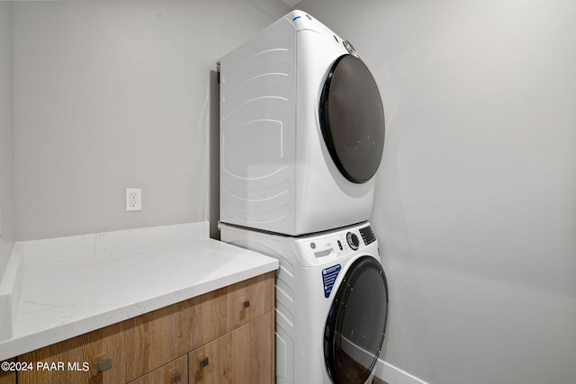 clothes washing area featuring cabinet space and stacked washer / drying machine