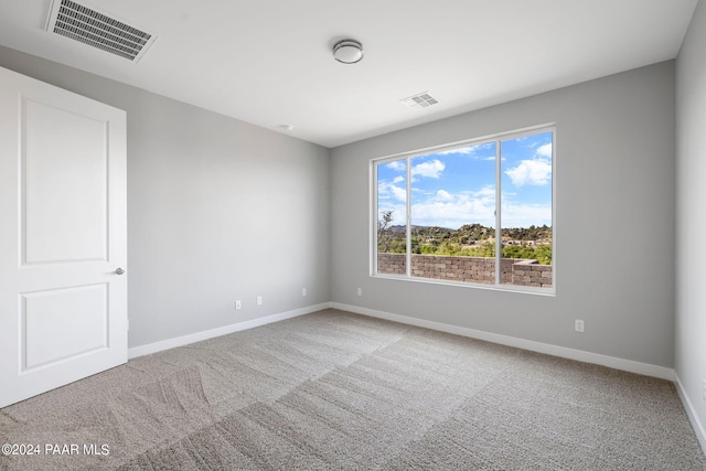 spare room with carpet, visible vents, and baseboards