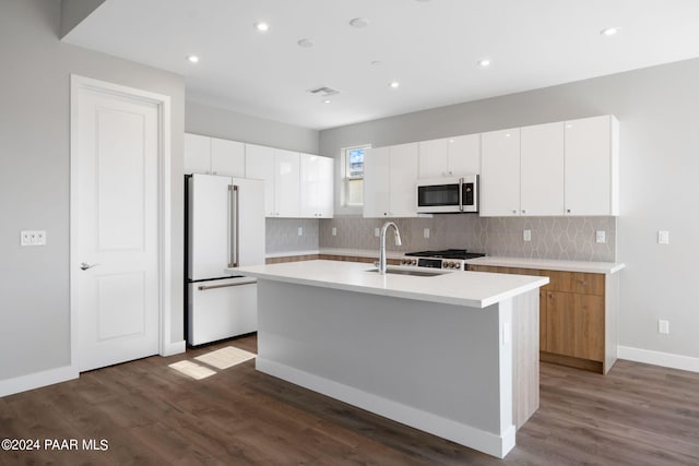 kitchen with an island with sink, white appliances, tasteful backsplash, light countertops, and a sink