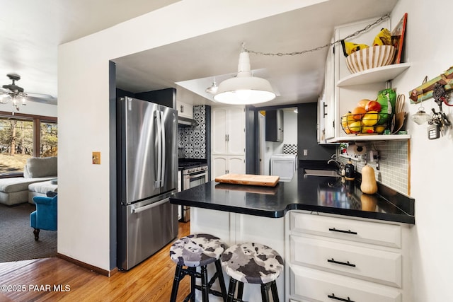 kitchen with light hardwood / wood-style floors, tasteful backsplash, white cabinetry, stainless steel refrigerator, and sink