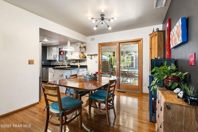 dining area with light hardwood / wood-style floors and a notable chandelier