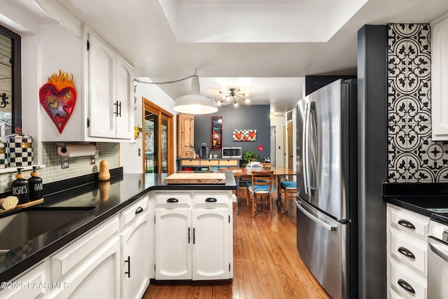 kitchen featuring light hardwood / wood-style flooring, stainless steel fridge, white cabinetry, and kitchen peninsula