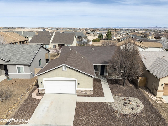 4786 N Edgemont Rd, Prescott Valley, AZ 86314 - view of front facade featuring a residential view, concrete driveway, a garage, stone siding, and stucco siding