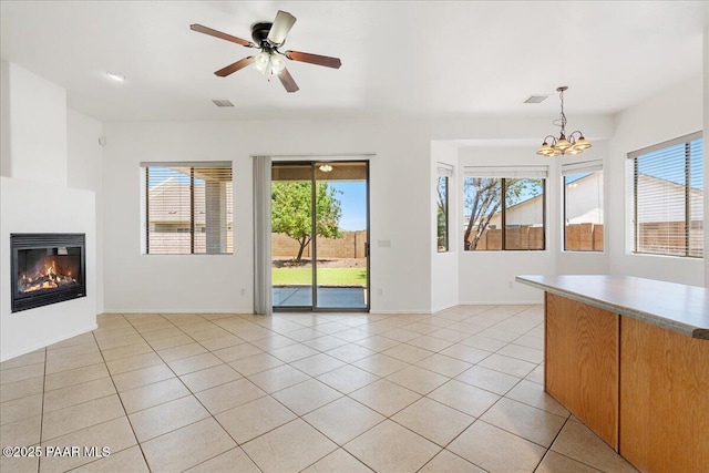 4786 N Edgemont Rd, Prescott Valley, AZ 86314 - unfurnished living room featuring a glass covered fireplace, a chandelier, healthy amount of natural light, and light tile patterned flooring
