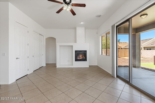4786 N Edgemont Rd, Prescott Valley, AZ 86314 - unfurnished living room with a glass covered fireplace, ceiling fan, light tile patterned floors, and arched walkways