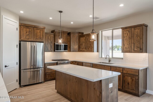 kitchen featuring appliances with stainless steel finishes, a sink, light wood-style floors, recessed lighting, and tasteful backsplash