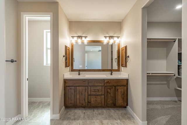 bathroom with double vanity, a spacious closet, and baseboards