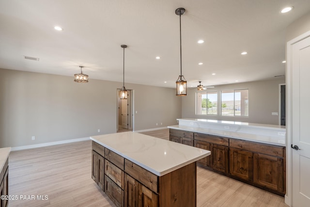 kitchen featuring light wood finished floors, open floor plan, recessed lighting, a kitchen island, and a ceiling fan