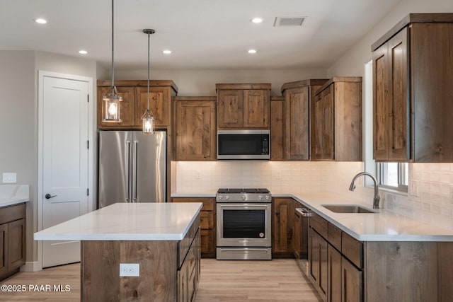 kitchen with stainless steel appliances, a sink, light wood-style flooring, decorative backsplash, and recessed lighting