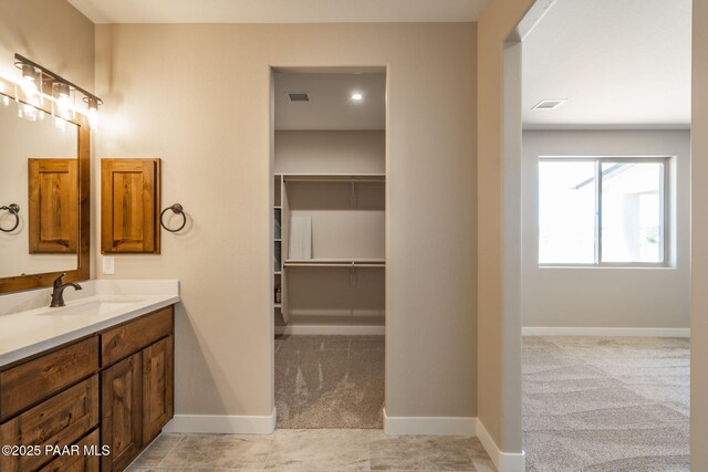 bathroom featuring vanity, baseboards, and a walk in closet