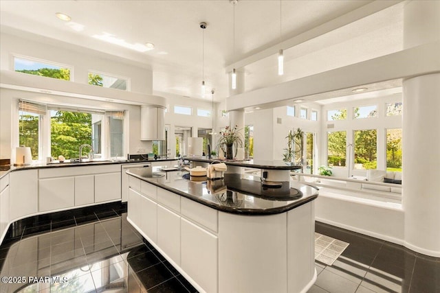 1369 Sierry Peaks Dr, Prescott, AZ 86305 - kitchen featuring dark countertops, a center island, white cabinetry, a high ceiling, and decorative light fixtures