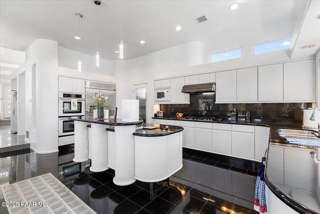 1369 Sierry Peaks Dr, Prescott, AZ 86305 - kitchen with exhaust hood, built in appliances, dark countertops, a center island, and backsplash