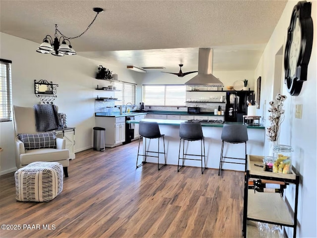 kitchen with open shelves, island range hood, wood finished floors, a peninsula, and black appliances