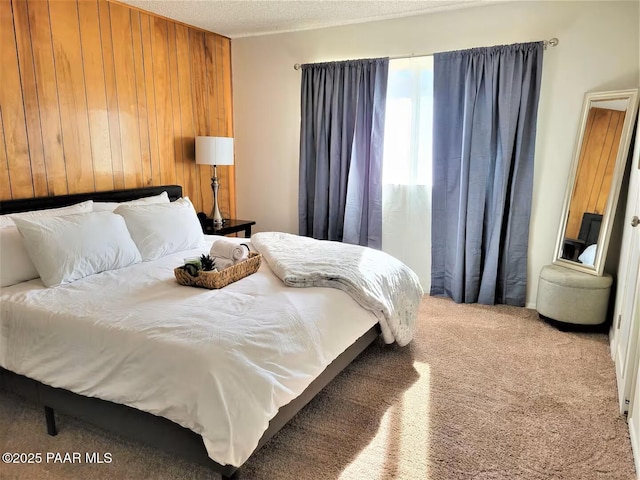 bedroom featuring carpet flooring, wooden walls, and a textured ceiling