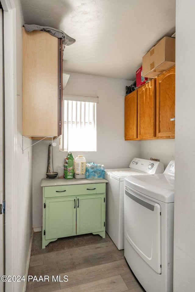 laundry room with washer and dryer, cabinets, and wood-type flooring