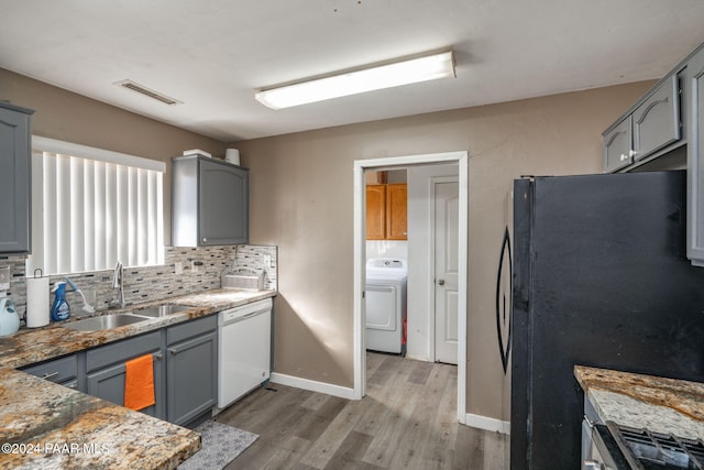 kitchen featuring sink, washer / clothes dryer, white dishwasher, gray cabinets, and black refrigerator