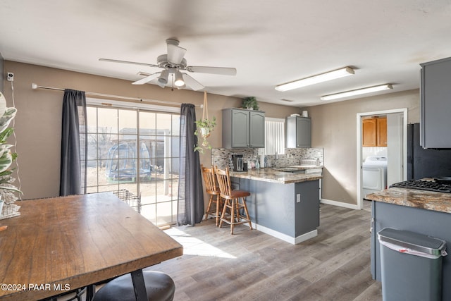 kitchen with hardwood / wood-style floors, ceiling fan, washer / dryer, and backsplash