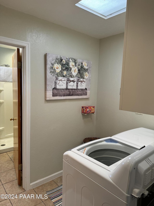 clothes washing area with washing machine and clothes dryer, a skylight, and light tile patterned floors