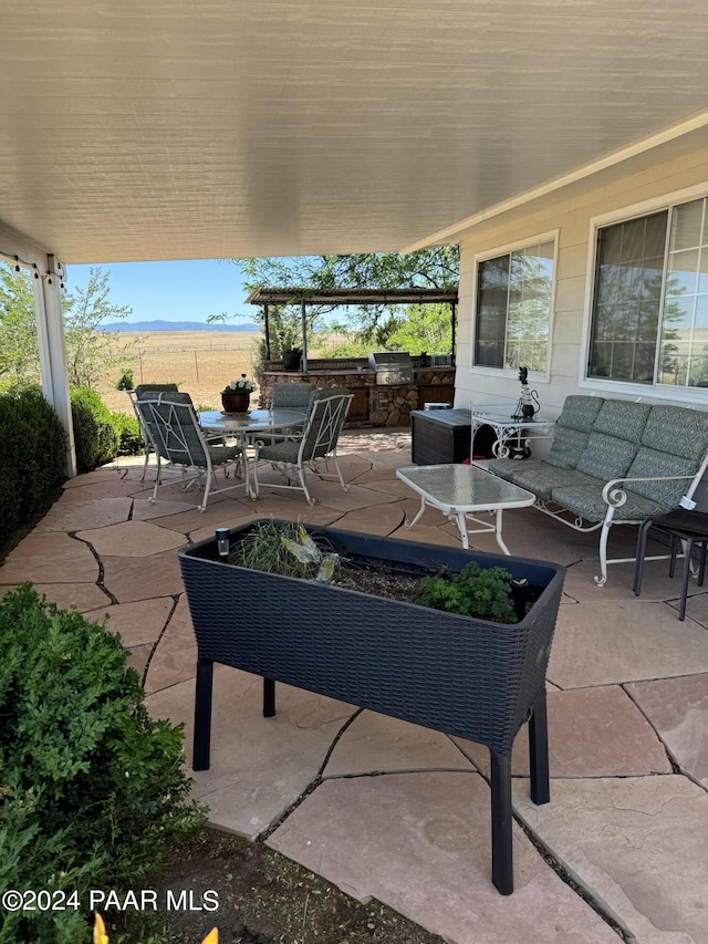 view of patio featuring an outdoor kitchen, a mountain view, an outdoor hangout area, and grilling area