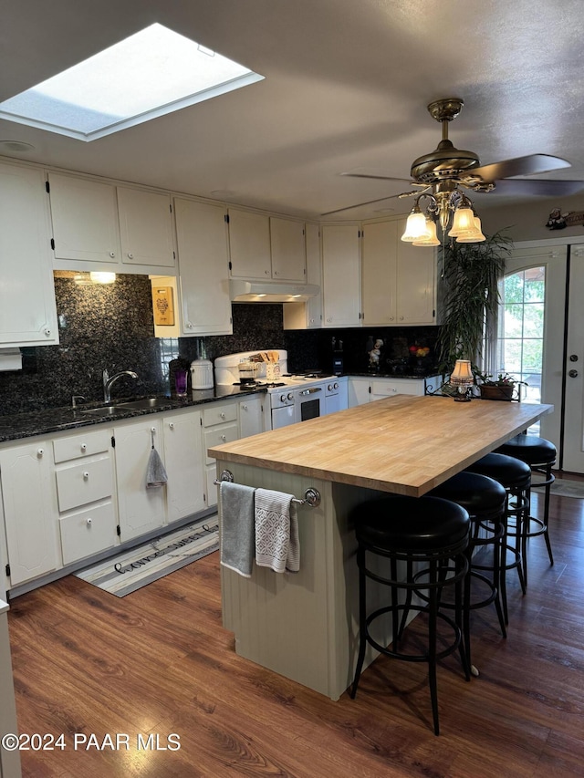 kitchen with a center island, dark wood-type flooring, wooden counters, white cabinets, and a skylight