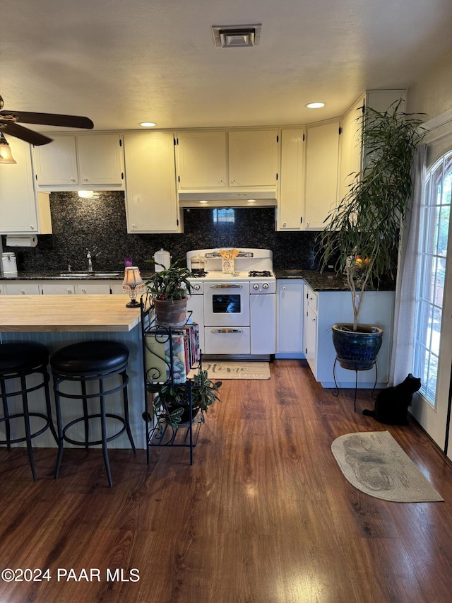 kitchen with dark wood-type flooring, white range with gas stovetop, sink, decorative backsplash, and white cabinetry