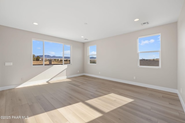 unfurnished room with a mountain view and light hardwood / wood-style floors