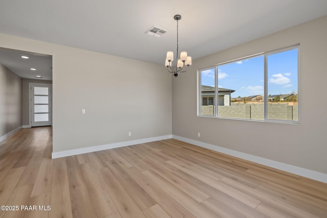 unfurnished room with a chandelier and light wood-type flooring