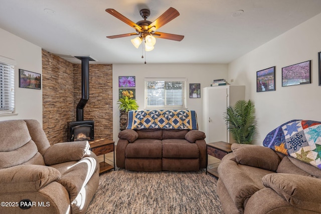 living area with a wood stove and ceiling fan