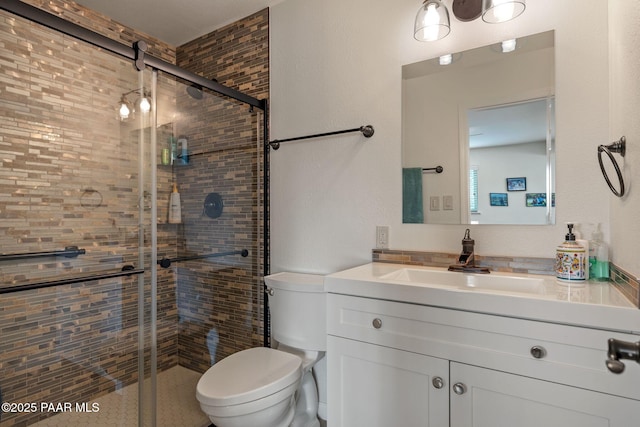 bathroom featuring a shower stall, toilet, and vanity