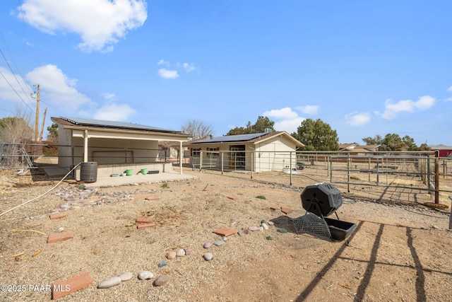 rear view of property featuring an outdoor structure, roof mounted solar panels, and an exterior structure