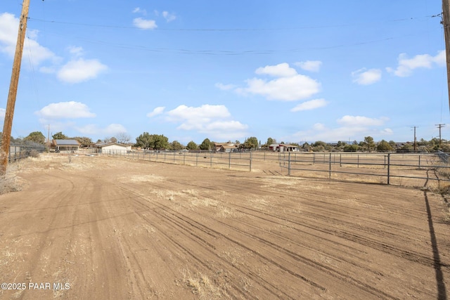 view of yard with an enclosed area, a rural view, and fence