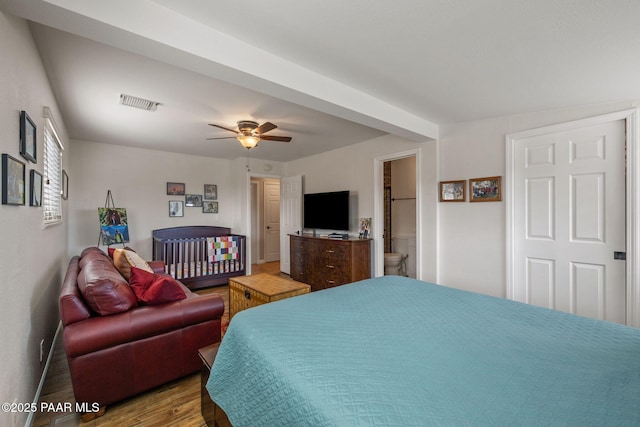 bedroom featuring visible vents, a ceiling fan, wood finished floors, and ensuite bathroom