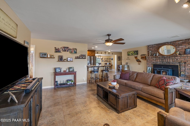 living room featuring light tile patterned floors, baseboards, a brick fireplace, and ceiling fan