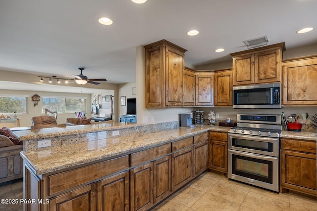 kitchen featuring light stone counters, visible vents, a peninsula, appliances with stainless steel finishes, and open floor plan