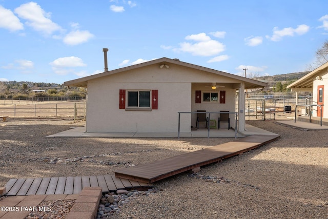 back of property with stucco siding, a ceiling fan, and a patio area