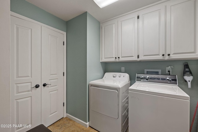 laundry room featuring washer and dryer, baseboards, and cabinet space